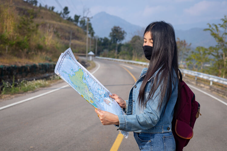 女孩旅游女孩在地图上寻找正确的方向亚洲背包地图