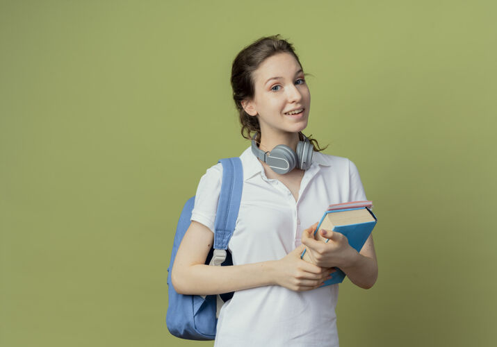 拿着给年轻漂亮的女学生留下了深刻的印象 她背着书包 脖子上戴着耳机 手里拿着书和记事本脖子穿漂亮
