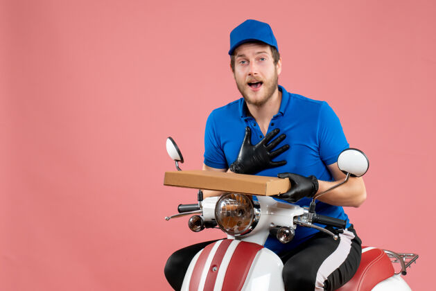 颜色正面图男性信使坐在自行车上 拿着一个粉红色的比萨饼盒人工人比萨饼