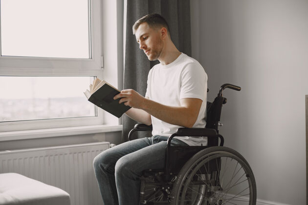 年轻人残疾的年轻人坐在轮椅上看书 呆在家里房子男性成人