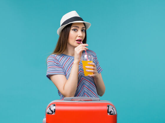 旅行前视图度假妇女与她的红色袋子举行浅蓝色背景她的果汁旅行度假女性果汁人包