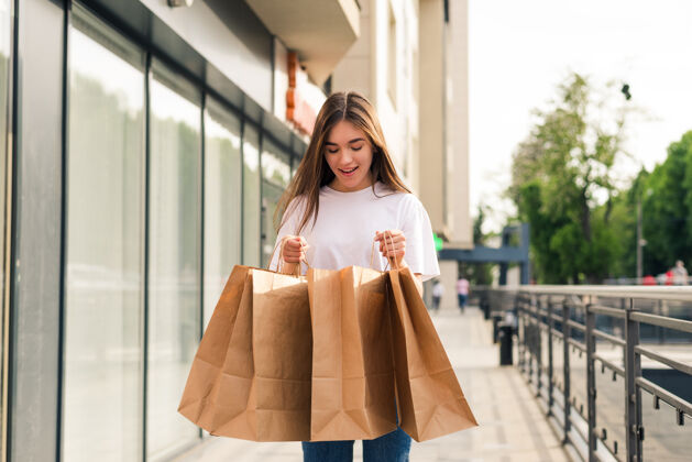 消费主义卖场 购物 旅游 快乐人理念——美丽的女人带着购物袋在城市里零售城市微笑