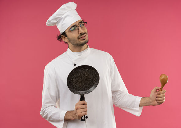 薯条看着身边困惑的年轻男厨师穿着厨师制服 戴着眼镜 手里拿着煎锅和勺子烹饪持有眼镜