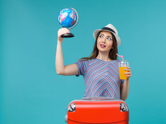 航行前景度假女人抱着果汁和地球仪在蓝色的地板上海上旅行度假暑假旅行人世界成人