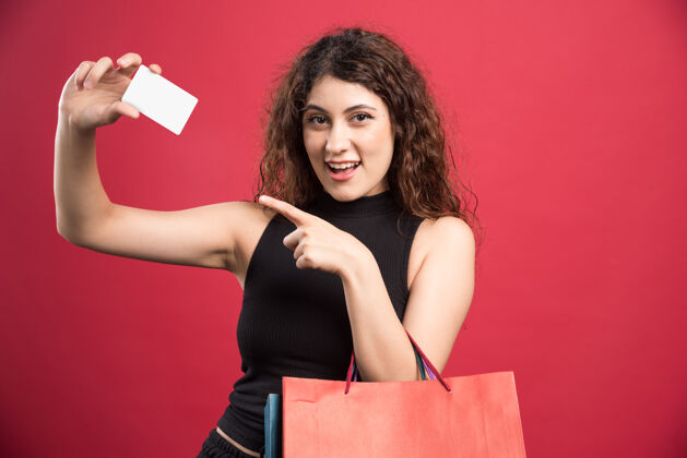 女人快乐的女人带着许多包和银行卡上的红色购物者包购物