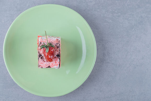 部分新鲜草莓蛋糕片放在绿色盘子里餐厅烹饪盘子