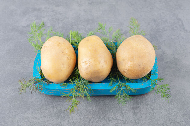 美味一块蓝木板 上面放着生土豆和新鲜莳萝食物香草新鲜