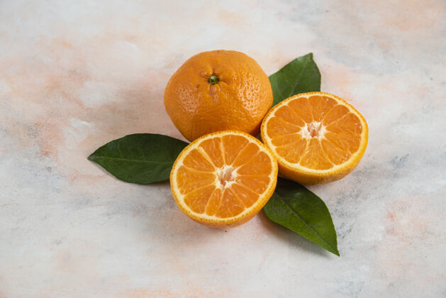 柑橘全切和半切的桔梗 叶子覆盖在五颜六色的表面上素食热带生的