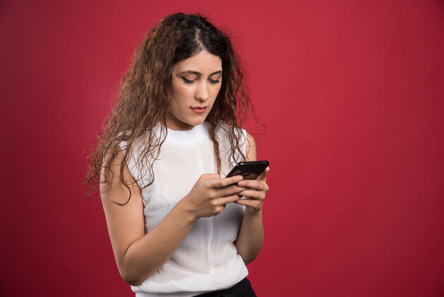 年轻人惊讶的女人正在红色的手机上输入什么打字短信时尚