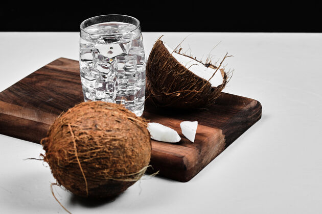 景观在木板上切半个椰子和一杯加冰的水有机水果食物