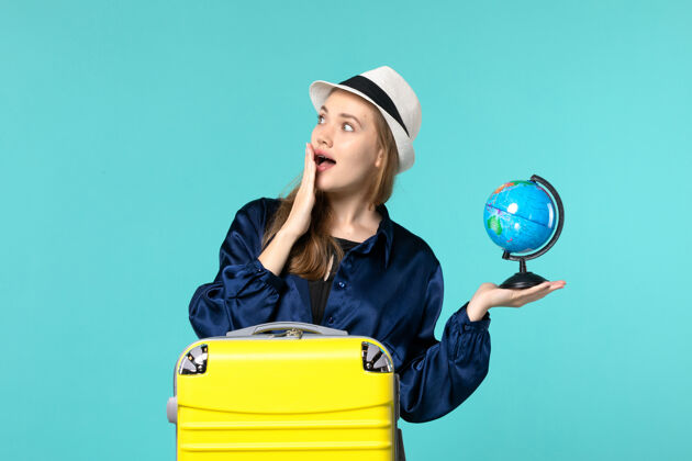 女性前视图年轻女子拿着地球仪 准备在蓝色背景上度假女性度假旅行海上飞机旅程美女肖像