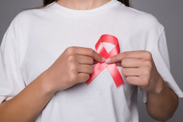 人世界乳腺癌日的概念 保健-妇女穿白色t恤与粉红丝带的认识 象征性的蝴蝶结颜色提高人们对妇女乳腺肿瘤疾病的生活身体意识形状