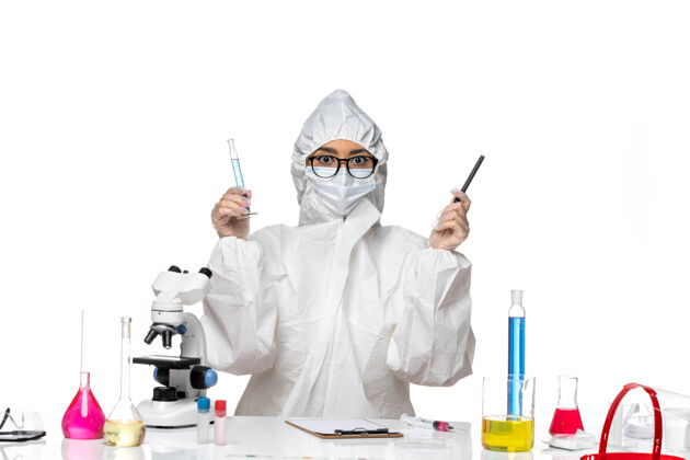 套装正面图身穿特殊防护服的年轻女化学家拿着小烧瓶 背景是白色的实验室冠状病毒化学病毒诊所个人实验室