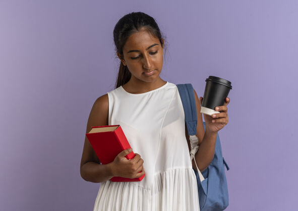 穿看着那个背着书包的年轻女学生 手里拿着一本书和一杯咖啡 背景是紫色的背紫色拿着