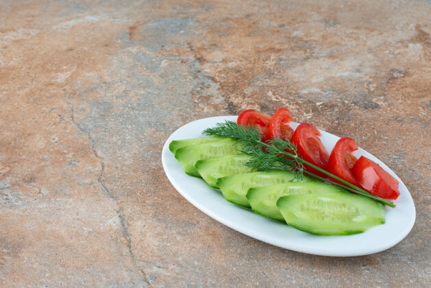 西红柿一个白色的盘子 上面放着黄瓜片和西红柿食物盘子白色