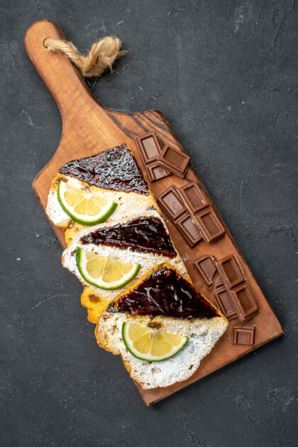 甜点俯视图美味的蛋糕片与巧克力条在黑暗的表面木头美味肉