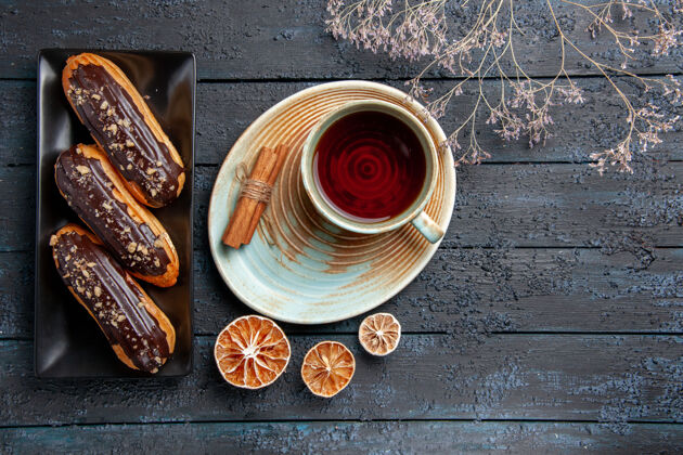 咖啡俯瞰矩形板上的巧克力蛋糕和一杯茶干柠檬和肉桂放在黑木桌上 有自由空间柠檬顶部早餐
