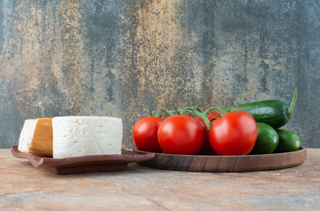 西红柿西红柿和黄瓜加奶酪放在大理石上奶酪木头美味