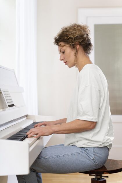 娱乐一个金发女人弹钢琴的侧视图垂直休闲室内