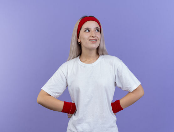 手微笑的年轻白人运动女孩戴着背带和头带腰背带头带