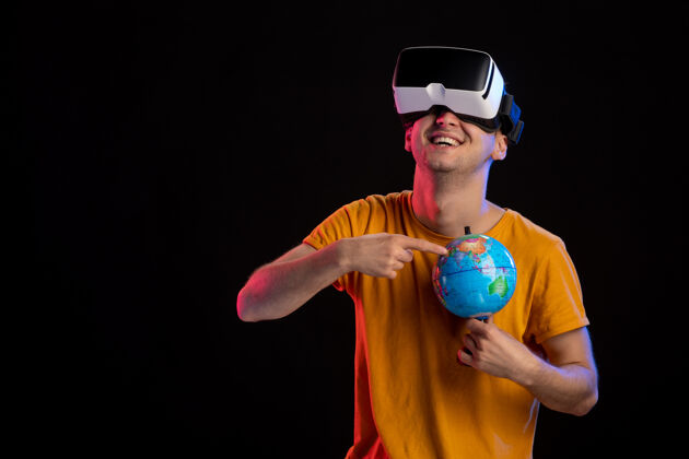 虚拟在黑暗的表面上玩虚拟现实拿着地球仪的年轻男性男性成人游戏