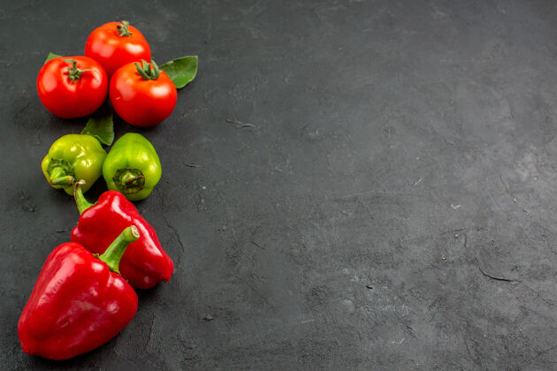 甜椒前视图新鲜的红色西红柿和甜椒在黑暗的背景西红柿食物胡椒