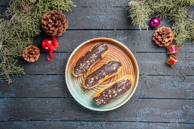 蜡封俯瞰巧克力椭圆板上的椭圆松果圣诞玩具冷杉树叶黑木桌上的免费空间桌子食物健康