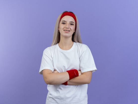手臂微笑的年轻白人运动女孩戴着背带和头带年轻头带运动