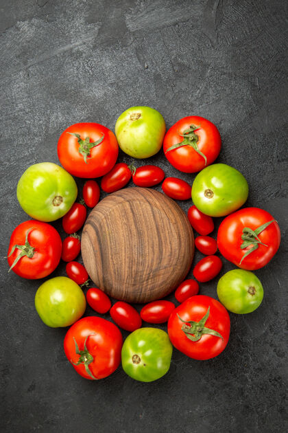 吃苹果顶视图樱桃红色和绿色的西红柿围绕着一个黑暗的地面上的木盘与自由空间西红柿盘子素食者