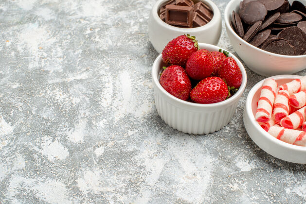 研磨在灰白色背景的右上角 底部是草莓 糖果和巧克力的近景碗浆果多汁农产品