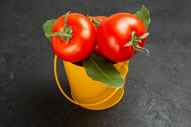西红柿底图一桶番茄和月桂叶在黑暗的背景底部配料叶子