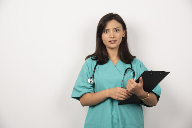 制服医生用听诊器和剪贴板看起来惊讶的白色背景高品质的照片女性职业剪贴板