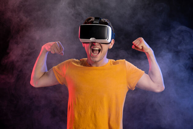 游戏帅哥戴着虚拟现实耳机在黑暗的表面男性游戏耳机