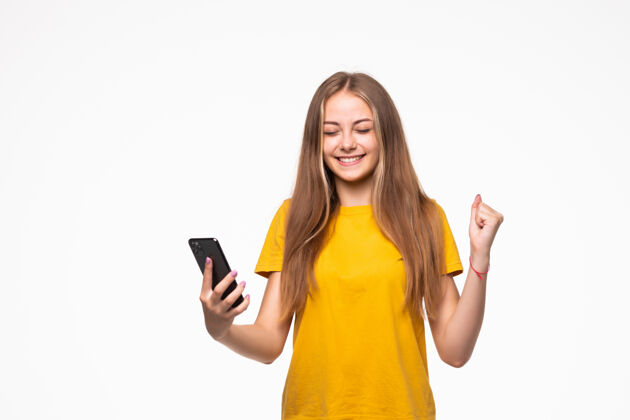 手机一位面带微笑的休闲女士在白墙上举着智能手机的画像成年人电话微笑