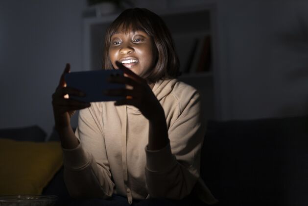 Netflix笑眯眯的非洲裔美国女人在家看netflix电影手表用户