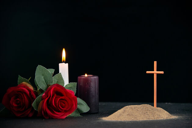 死亡在黑暗的表面上有蜡烛和鲜花作为记忆的小坟墓烛光花表面