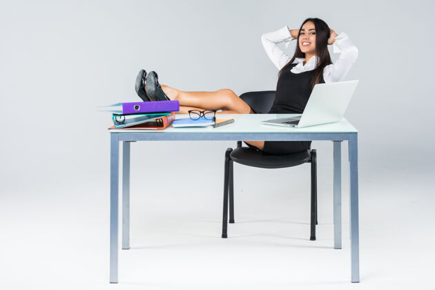 互联网年轻轻松的商务女士 双腿放在工作台上 享受工作日的结束 与世隔绝执行官办公室胜利