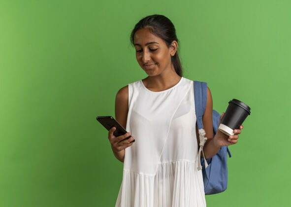 抱着高兴的小女生背着书包 手里拿着一杯咖啡 看着手机年轻咖啡杯子