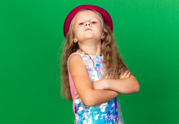 生日自信的金发小女孩 头戴紫色派对帽 双臂交叉 站在绿色墙壁上 留有复制空间自信交叉小