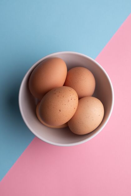 顶视图四个鸡蛋放在一个蓝色和粉色的碗里营养庆祝食物