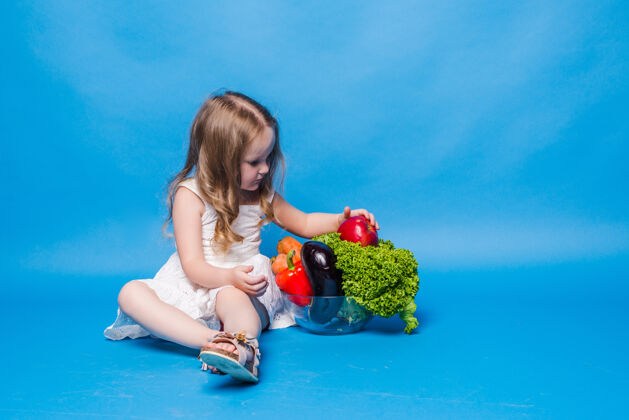 可爱蓝色墙上挂着蔬菜的小女孩漂亮孩子蔬菜