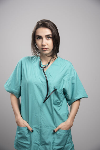 职业带听诊器的女医生站在灰色背景上高质量照片医疗制服成人