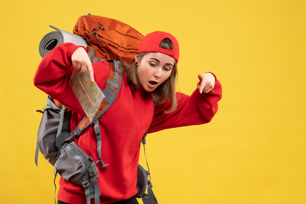 背包正面图漂亮的女旅行者背着背包拿着地图指着地板时尚帽子地图