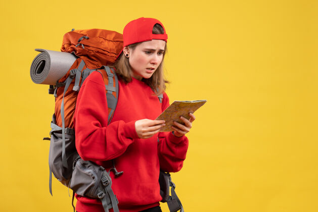地图前视图困惑的女背包客在看旅游地图阅读帽子前面