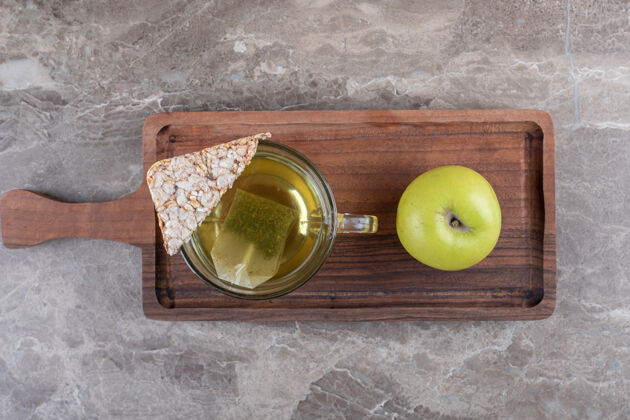 纸板一块膨化的年糕 茶和苹果 在木制托盘上 在大理石背景上美味美味年糕