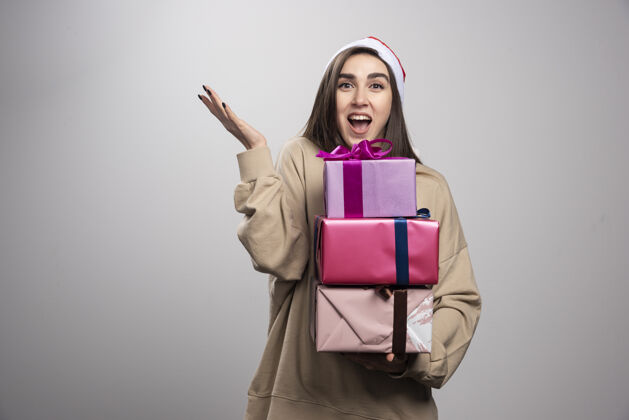 抱着年轻女子拿着三盒圣诞礼物表情站着兴奋