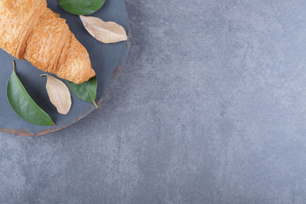 自制法国羊角面包在灰色木板上的特写照片木头面包房美食
