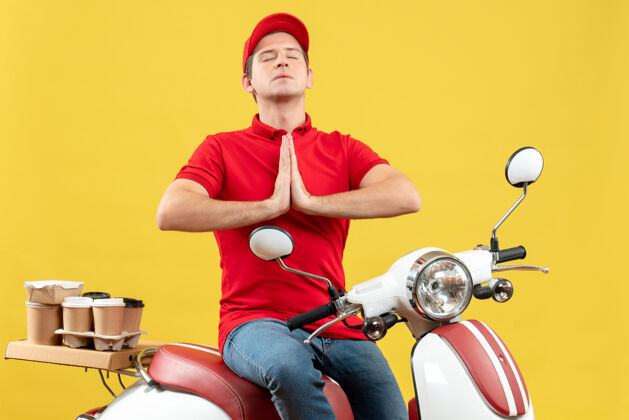年轻人顶上是一个身穿红色上衣 戴着帽子的充满希望的年轻人 在黄色背景下传递着祈祷的命令帽子摩托车黄色