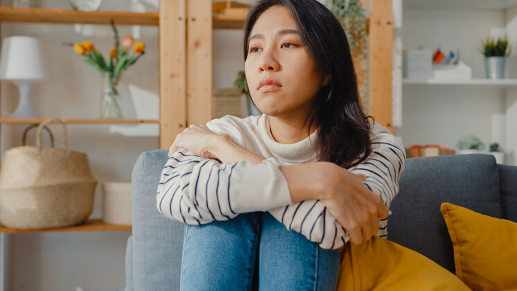 女人体贴的亚洲女士坐在一起感到孤独 感到沮丧 独自呆在家里隔离感情生病
