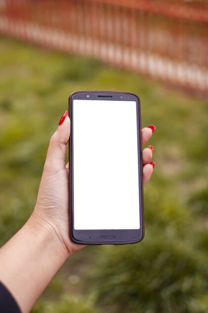 信息垂直拍摄一位女性拿着一个空白屏幕的手机 涂着红色指甲油现代触摸手机